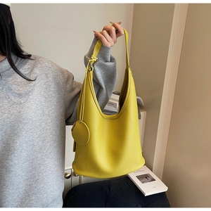 Detail of a bright yellow pebbled leather hobo bag with a matching round coin purse charm