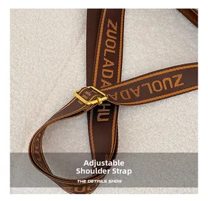 Close-up of adjustable woven shoulder strap with gold buckle and lettered pattern