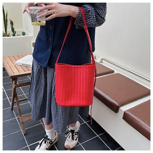 Close-up of red woven bucket bag with fine leather texture and adjustable strap