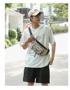 Detail of beige and black crossbody chest bag featuring bungee cord design and utility pockets