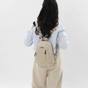 Détail d'un mini sac à dos beige avec bretelles réglables et poche zippée à l'avant