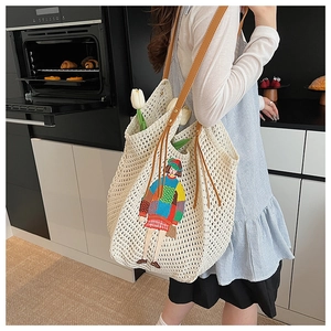 Detail of crochet knit tote bag featuring cartoon embroidery and brown leather strap