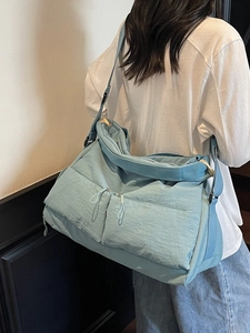 Large light blue nylon crossbody tote bag with adjustable strap shown on model back
