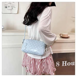 Detail of light blue polka dot crossbody bag featuring a 3D letter B and pearl charm
