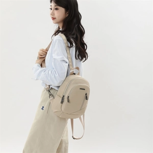 Détail du sac à dos multifonctionnel beige avec logo métallique et sangle réglable