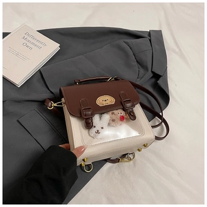 Detail of color-block satchel featuring transparent window with plush animal decorations