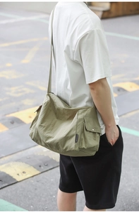 Détail du sac de messager vert armée montrant la poche latérale et le tissu en nylon