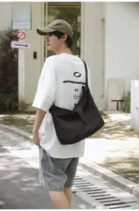 Detail of black canvas crossbody bag with adjustable strap worn by model in casual style