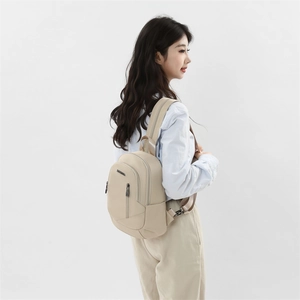 Détail du sac à dos beige en nylon avec fermeture éclair verticale et plaque de marque