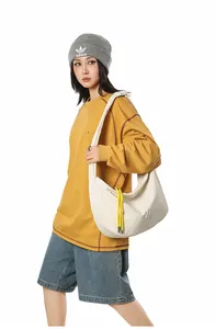 Detail of off-white crescent crossbody bag featuring yellow drawstring and grid texture