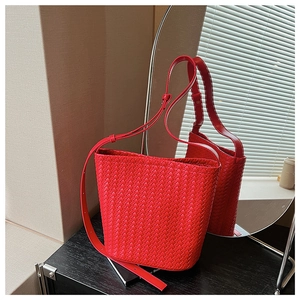 Detail of red leather woven bucket bag with adjustable strap and intricate intrecciato pattern
