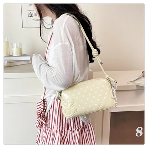 Close-up of yellow glossy shoulder bag with white polka dots and pearl chain detail