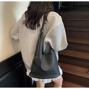 Detail of black lychee grain leather bucket bag with shoulder strap on a model