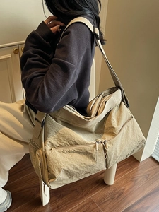 Minimalist khaki nylon messenger bag with wrinkled texture and wide shoulder strap