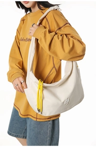 Detail of off-white hobo bag showing checkered fabric texture and yellow braided rope charm