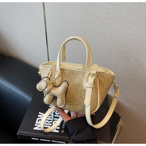 Detail einer beige Monogramm-Tragetasche mit Hundeanhänger und goldener Hardware