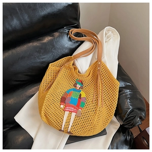 Detail of yellow knit tote with cartoon girl embroidery and brown leather straps