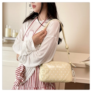 Detail of yellow polka dot crossbody bag with 8-shaped patch and pearl tassel charm