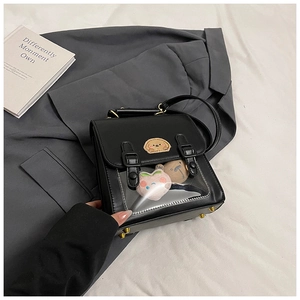Detail of black ita bag with transparent window, plush charms and metallic feet
