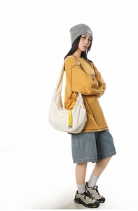 Detail of white dumpling bag with yellow drawstring and plaid texture on model