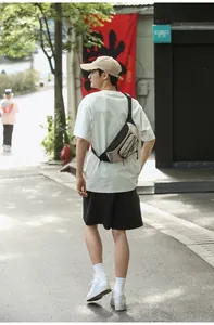 Outdoor view of a black and beige dual-tone chest bag worn with casual summer sportswear