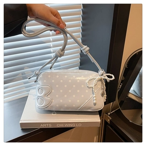 Close-up of light blue polka dot shoulder bag with 3D B logo and pearl bow charm detail