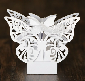 Macro shot of white hollow butterfly candy box with laser-cut patterns and white ribbon