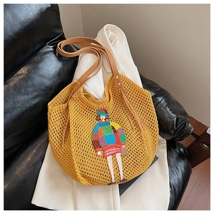 Detail of yellow knit tote with cartoon embroidery and brown leather straps on sofa