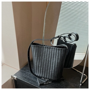 Detail of premium black woven leather bucket bag with wide cross-weave texture design