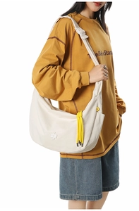 Close-up of white mesh hobo bag with yellow woven tassel and embossed logo detail