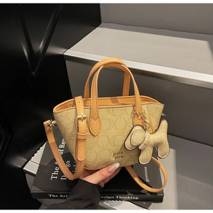 Detail der Handtasche mit Monogramm-Jacquard, Ledergriffen und dekorativem Hundeanhänger