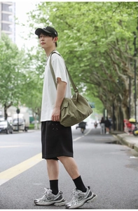 Détail du sac bandoulière en toile vert armée avec poche cargo latérale et sangle