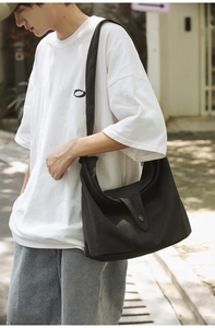 Outdoor model shot of large black canvas crossbody bag with flip-top buckle closure