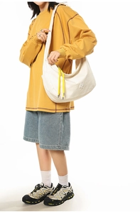 Detailed side view of white nylon hobo bag with yellow zipper pull on female model