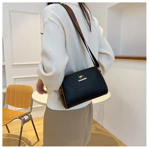 Detail of black woven texture Boston bag with golden kangaroo logo and wide strap