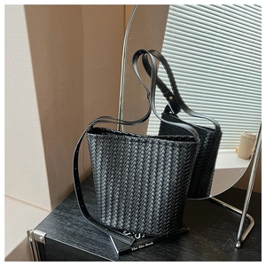 Detailed close-up of premium black woven leather bucket bag texture and shoulder strap