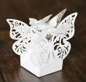 Detailed laser-cut white wedding favor box with a delicate butterfly design and silk ribbon