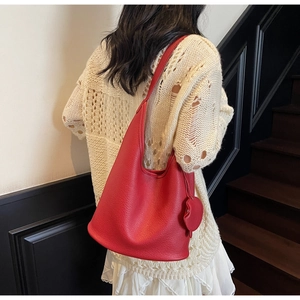 Close-up of red leather bucket tote bag with lychee texture and heart charm pendant