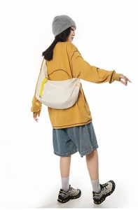 Detail of minimalist moon-shaped crossbody bag with yellow zipper and logo on white background