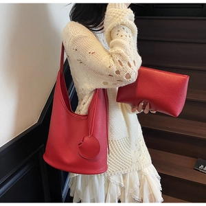 Detail of red lychee grain leather tote bag set with matching zipper pouch on model