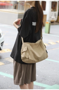 Détail du sac messager en nylon kaki montrant la grande poche latérale et l'étiquette