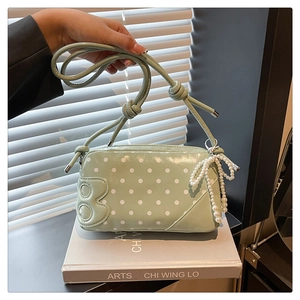 Close-up of light green polka dot crossbody bag with beaded pearl bow and side number 8