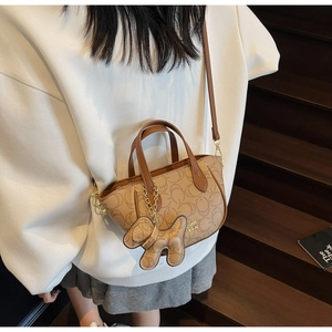 Detail der geprägten Canvas-Handtasche mit Lederbesatz und dekorativem Hundeanhänger