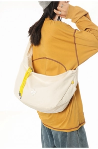 Detail of off-white dumpling bag with yellow drawstrings and textured nylon fabric