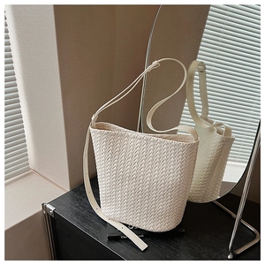 Detailed view of white woven bucket bag with adjustable shoulder strap and crossbody design