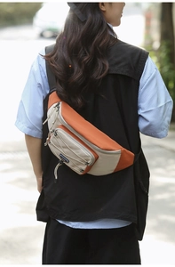 Close-up of orange and beige outdoor crossbody bag with functional drawstring detail