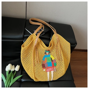 Close-up of yellow knit tote bag featuring colorful girl embroidery and faux leather handles
