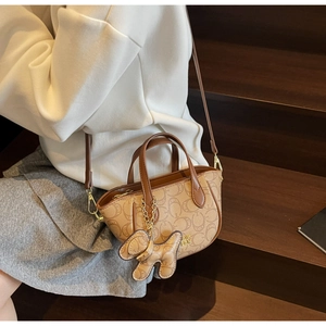 Detailansicht der braunen Monogramm-Handtasche mit Ledergriffen und Hunde-Anhänger