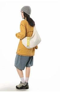 Detail of white hobo bag with yellow drawstrings and waterproof textured fabric