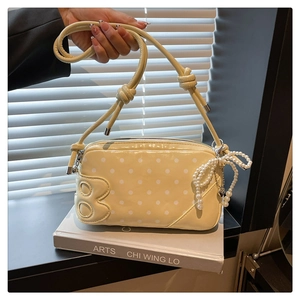 Detail of yellow polka dot shoulder bag with B-logo and elegant pearl bow charm